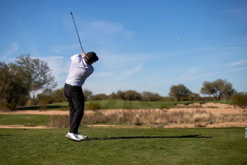 Golfer mid-swing under an Arizona sky