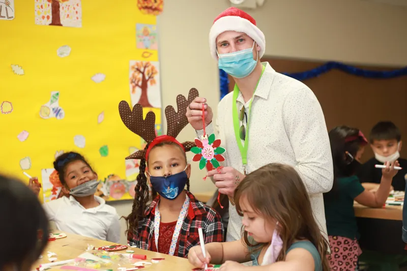 Kids doing holiday crafts with a Fore The Kids volunteer