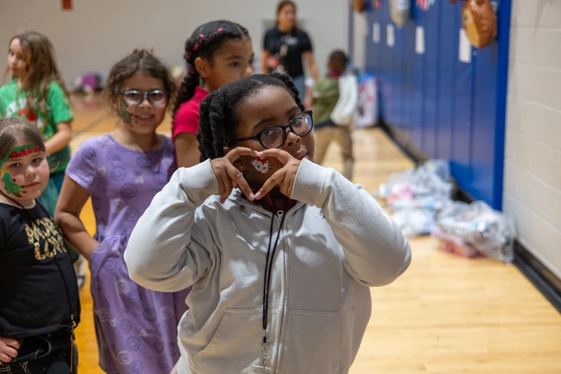 A girl makes a heart with her hands at a Fore The Kids event at the Boys and Girls Club